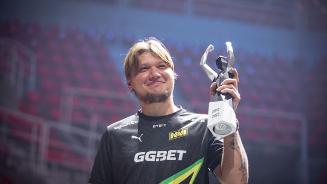 S1mple, un jugador de Counter-Strike, vistiendo una camiseta de NAVI y levantando un trofeo en un estadio.